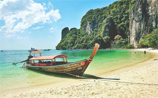 เรือหางยาวจอดริมหาดทรายขาวใต้ผาหินปูนกระบี่